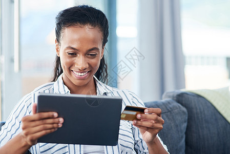 我要买下这个 一个年轻女人 在家里用信用卡和数字平板电脑做客背景图片