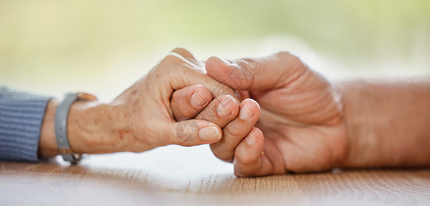 一对老年夫妇 手牵着手 在餐桌上寻求安慰 爱或帮助 以表达同情 痛苦或同情 老人 老妇人和在家中以同理心 信任和关怀帮助他们建立图片