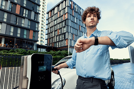 进步商务人士 智能手表 在公共电讯站的EV汽车商业检查商务力量公寓车辆技术住宅人士会议图片