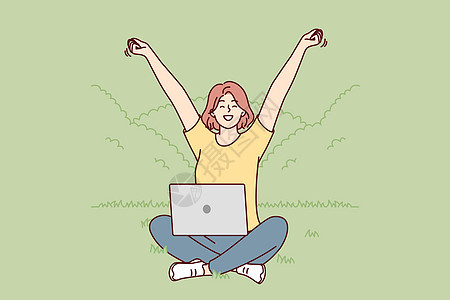 坐在公园草坪上的快乐女人 膝盖上带着笔记本电脑 双手举高图片