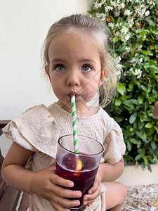 小女孩喝果汁 用一根吸管 从玻璃杯里拿着它图片