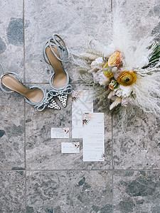 结婚花束站在新娘鞋旁边的一块瓷砖上 请柬和戒指图片