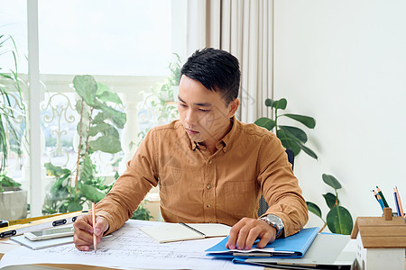 在办公室工作的亚洲英俊男建筑师建筑学男人商业职场电脑桌子笔记本人士蓝图商务图片