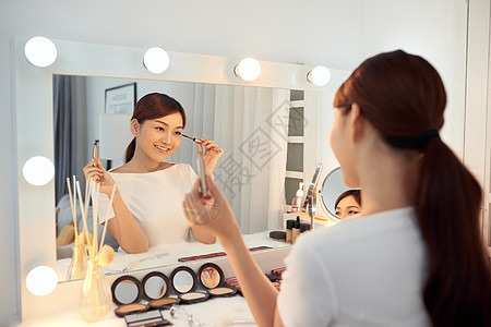 年轻亚洲女性在镜子前申请化妆涂擦眼睫毛 专注她的反光眼睛女孩女士睫毛膏魅力化妆品刷子灰色图片