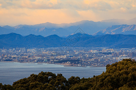 美丽的日落颜色 天空在山上和横越海岸的城市图片