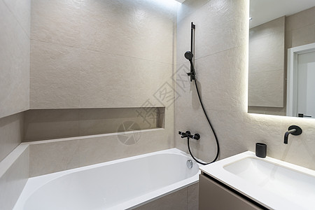 现代风格的浴室 铺有灰色和白色瓷砖 有一面带夜光灯的大镜子 带木抽屉和水槽的桌面 带淋浴和玻璃隔断的浴缸 毛巾架和衣架装饰公寓木图片