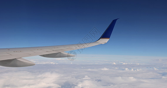 在一片阴暗的云天背景中 看到飞机机翼从窗口飞过云层上方图片