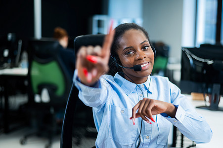 年轻的非洲女性在耳机上与客户交谈 快乐的女呼叫中心员工呼叫操作员热线会议帮手爆炸商务女孩求助工作图片