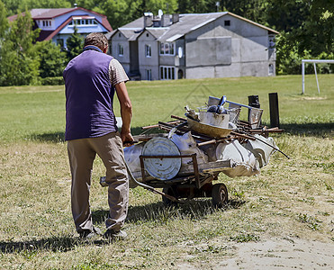 一个男人带着生锈的旧东西 扔在推车上 例如生锈的锌图片