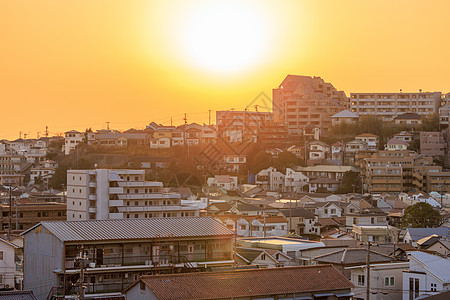 浓密社区房屋和公寓楼被橙色太阳遮盖图片