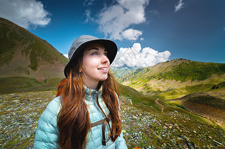 一个微笑的女人在登山时休息的画像 一个背着背包的女人站在山上欣赏美景 快乐的游客图片