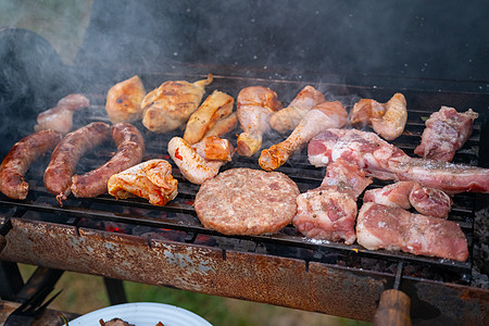 在烧烤会上把美味的烤肉和蔬菜 放在煤炭上炙烤野餐草地花园香肠烹饪牛肉午餐烧伤季节图片