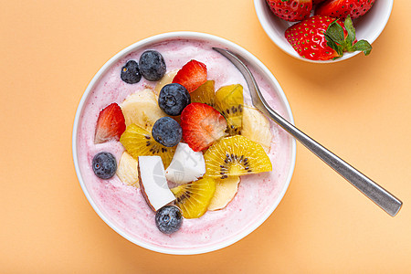 健康早餐或甜点酸奶碗 配有新鲜香蕉 草莓 蓝莓 可可 基维风景最美的面纸背景和勺子图片