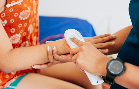 对女病人的现代激光理疗 手臂上使用激光疗法治疗疼痛 物理治疗师在患者手臂上使用激光疗法的特写图片