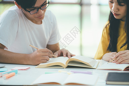 近身的亚裔学生正在阅读书本和学习 并一起教学团队老师青少年友谊大学中学朋友们课堂技术图书图片