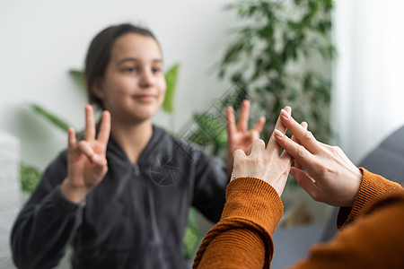 女儿用手语与中年母亲交谈 家人坐在扶手椅侧视 老师教青少年聋哑女孩视觉手手势符号概念形象图片