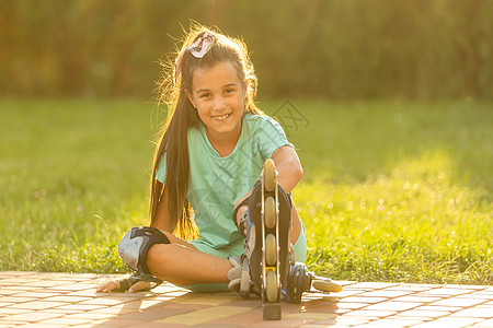 小女孩在公园中美丽的夏日穿溜冰鞋 穿着滑雪鞋滚筒运动活动孩子轮滑女孩乐趣喜悦滑冰溜冰者图片