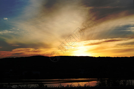 日落在山上射线环境反射橙子黄色太阳天空池塘丘陵色调图片