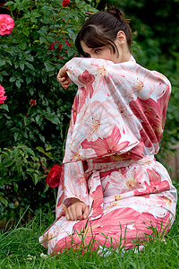女孩在一朵花的浴田袖子花园衬套女性玫瑰浴衣公园头发皮肤手臂图片