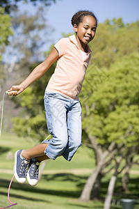 年轻女孩在户外笑着跳过绳子农村健康跳跃乐趣微笑享受孩子相机跳绳女性图片