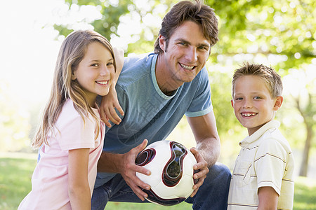 男子和两名幼儿在户外携带排球和米球公园女儿孩子教学女性儿子微笑享受男生男性图片