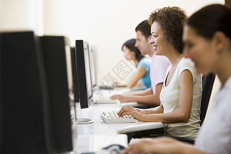 电脑房的四人打字和微笑女性雇员服饰水平团队桌子团体文书职员商业图片