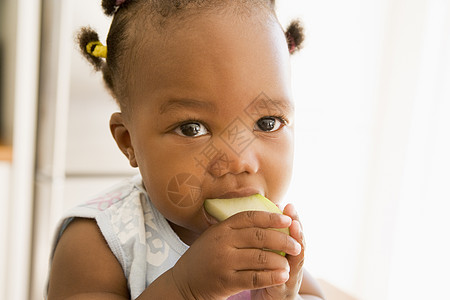 女孩在室内吃苹果倾斜孩子女性享受食物小吃头肩水果水平视图图片