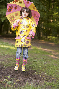 在户外的年轻女孩 带着雨伞跳跃和微笑图片