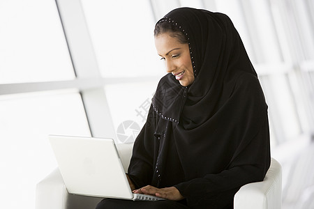 坐在室内 手持笔记本电脑微笑的妇女成年人生意人窗户通讯人士商务差分桌子一代衣服图片