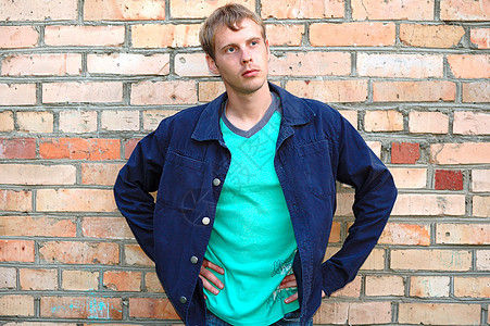 年轻时尚的人站在砖墙附近绿色衣服红色金发女郎男人衬衫蓝色黄色头发灰色图片