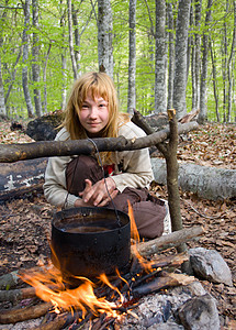 坐在森林中营火附近的女孩图片