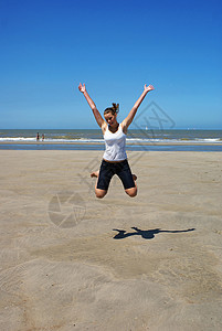 海滩上快乐的女孩青少年天空阴影晴天假期牛仔裤身体波浪金发蓝色图片