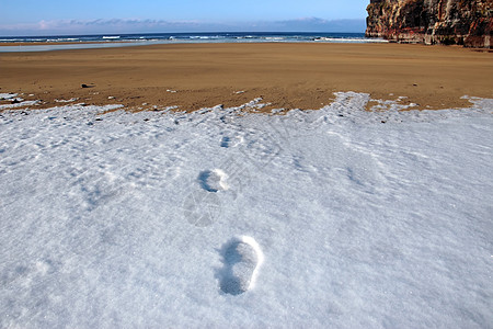 寒冷的冬季天空海滩上积雪脚印图片