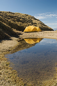 在小池塘附近设置黄色帐篷高度国家孤独高山风景海拔运动蓝色挑战庇护所图片