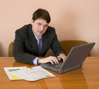 商务人士用笔记本电脑坐在桌子上工作微笑职场蓝色夹克笑脸套装金子男人写字桌图片