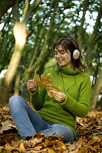 监听音乐耳机乐趣黑发享受女性喜悦女士幸福树叶公园图片