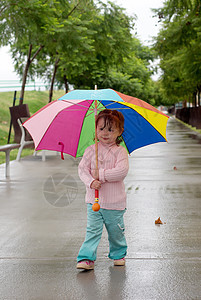 带着雨伞的小女孩在雨下站着图片