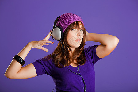 听音乐的美丽女子音乐黑发耳机姿势工作室紫色手机女孩冒充女士图片