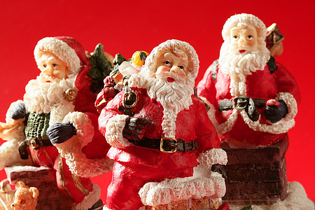 三个圣诞老人雕像 在红色背景 工作室父亲塑像装饰品帽子孩子传统季节礼物庆典喜悦图片