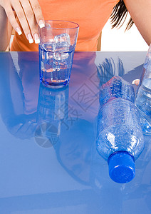 年轻女孩饮水饮用水蓝色享受瓶子橙子食物意识身体桌子影棚生活方式图片