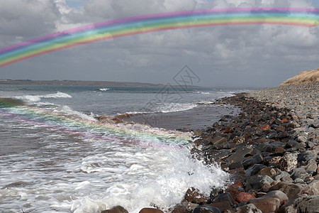 带彩虹的鹅卵石上滚动的波浪图片