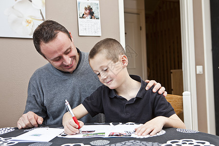 父亲帮助儿子做家庭作业学习男士阅读团结教育外展阶层小男孩快乐活动背景图片