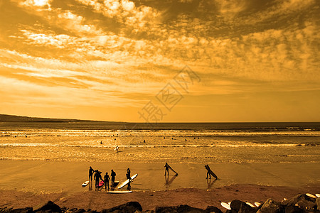 学生冲浪者光荣的日落海滩图片