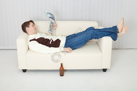 人舒适地躺在沙发上的啤酒和日记图片