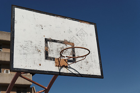 旧的破碎篮球圈 在院子操场对着蓝天圆圈环形木头运动戒指蓝色竞赛木板金属篮子图片
