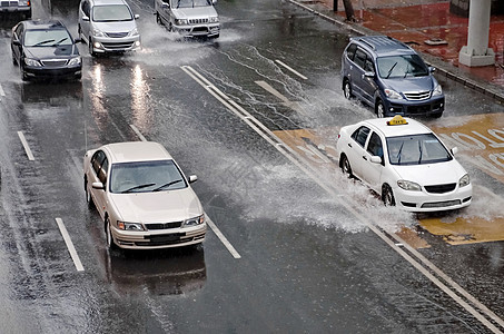 驾车在洪水泛滥的街道上风暴水坑红色城市雨水飞溅天气交通场景驾驶图片