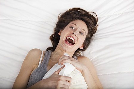 醒来后幸福快乐说谎健康福利女性黑发休息枕头睡衣卧室微笑图片