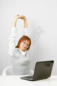 带膝上型电脑伸展的疲累女孩工作手臂微笑人士商务互联网管理人员女性时间办公室图片