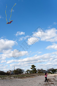 女孩飞行Kite在海滩上天空风筝蝴蝶尾巴闲暇空气航班海岸线微风享受图片