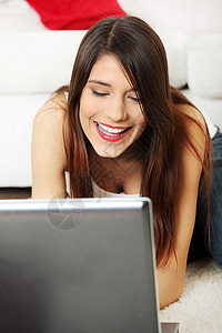 年轻女性用笔记本电脑躺在地板上闲暇学习女士技术互联网教育阅读地面微笑快乐图片